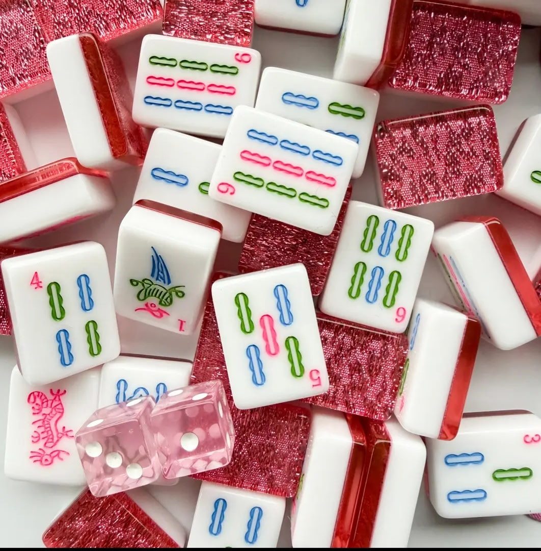 Close view of white Mahjong tiles with blue, green, and pink symbols and pink glitter backs